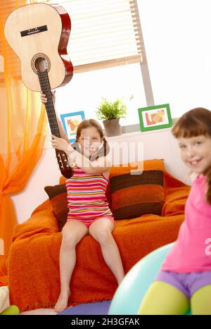 Ragazza che alza la chitarra alta dal collo Foto Stock