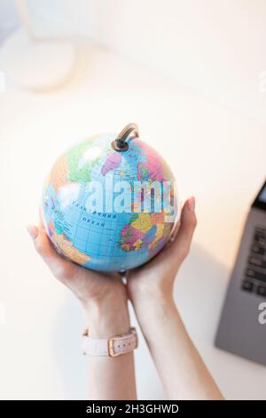 La donna tiene il globo nelle sue mani sopra il tavolo. Concetto di viaggio Foto Stock