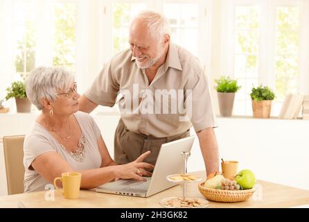 Coppia anziana felice con il computer a casa Foto Stock