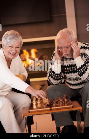 Coppia che gioca a scacchi in un accogliente soggiorno Foto Stock