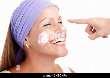 Ritratto di attraente giovane donna applicazione crema Foto Stock