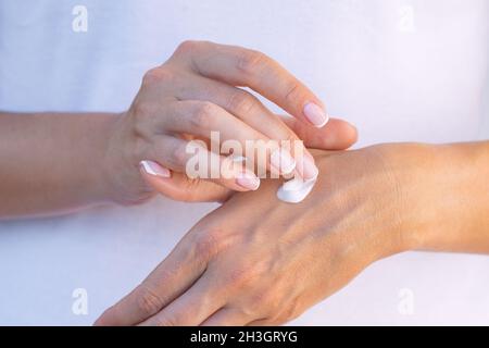 Primo piano delle mani della donna con idratante, lozione o crema per le mani. Protezione della pelle. Concetto di cura delle mani o della pelle Foto Stock
