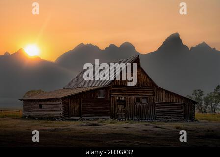 Bellissimo tramonto dietro una casa rustica al Grand Teton National Park in Wyoming, Stati Uniti Foto Stock