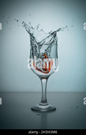 Una fragola gocciolata in un bicchiere di acqua Foto Stock