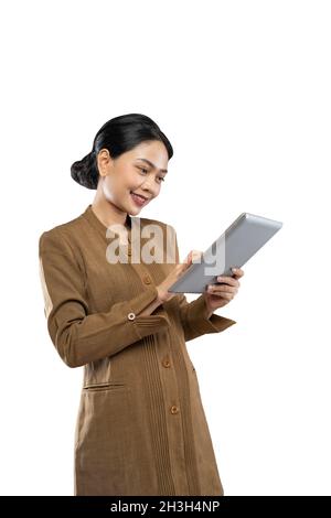 Donna indonesiana in uniforme di funzionario in piedi utilizzando un tablet per computer Foto Stock