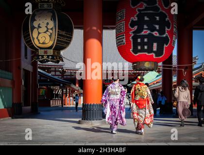 Due donne, vestite di kimono formale, passano attraverso un tempio a Tokyo, Giappone. Foto Stock