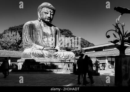 Alcuni turisti in piedi intorno al Grande Buddha, o Kamakura Daibutsu, la statua alta 43 piedi e 103 tonnellate è stata completata nel 1252 e si erge a Kamakur Foto Stock