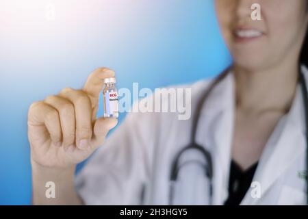 Un medico in cappotto bianco e stetoscopio intorno al collo sta tenendo una bottiglia di vetro di vaccino BCG che previene la tubercolosi, una sorta di infezione batterica Foto Stock