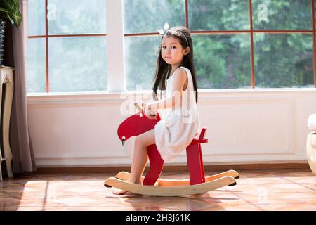 Carina bambina a cavallo di legno Foto Stock