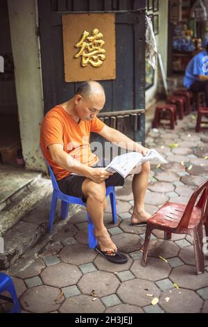 HANOI, VIETNAM - Aprile 8, 2015: vietnamita non identificato uomo che legge il giornale in strada, l'8 aprile 2015, ad Hanoi, Vietnam Foto Stock