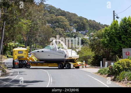 Grande camion che consegna una barca Sea Ray Cruiser ad un porto turistico a Bayview sulle rive di Pittwater, Australia Foto Stock