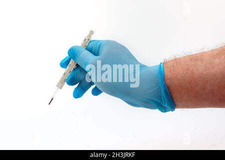 Mano dell'uomo in guanto di lattice blu che tiene il termometro medico isolato su sfondo bianco Foto Stock