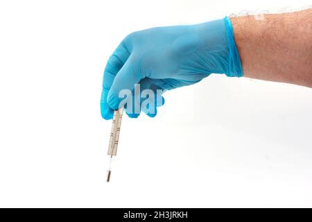 Mano dell'uomo in guanto di lattice blu che tiene il termometro medico isolato su sfondo bianco Foto Stock