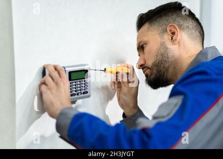 Il tecnico installa il comando del sistema di allarme di accesso antifurto Foto Stock