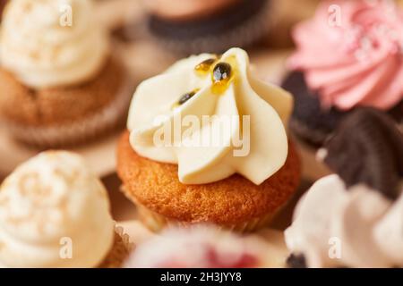 Piccolo cupcake con crema e crema di frutta passione come condimento per una festa di compleanno Foto Stock