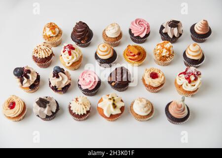 Un sacco di piccoli cupcake con decorazioni e condimenti Foto Stock