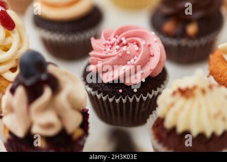Cupcake al cioccolato con crema di lamponi e perle di zucchero come decorazione Foto Stock