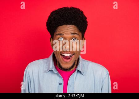 Ritratto di attraente allegro brunet ragazzo buon umore incredibile vendita isolato su sfondo rosso brillante Foto Stock