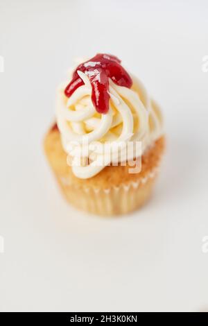 Piccolo cupcake con gelato agli spaghetti e salsa di fragole su sfondo bianco Foto Stock