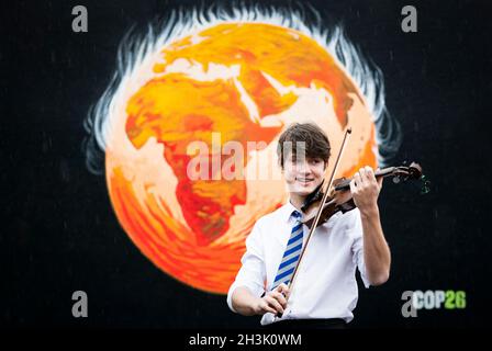 Il compositore e violinista Viktor Seifert, 14, della St Mary's Music School di Edimburgo, suona il violino Driftwood, di fronte al murale Climate Fringe alla St John's Church nel West End, davanti al COP26 a Glasgow. Data foto: Venerdì 29 ottobre 2021. Foto Stock