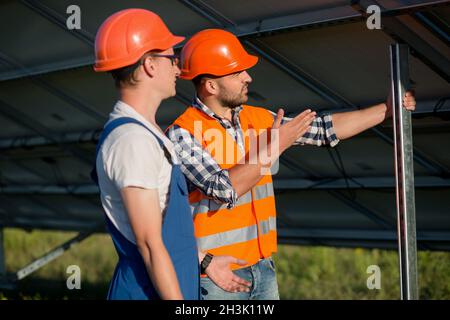 Lavoratori l'installazione di pannelli fotovoltaici a energia solare stazione. Foto Stock