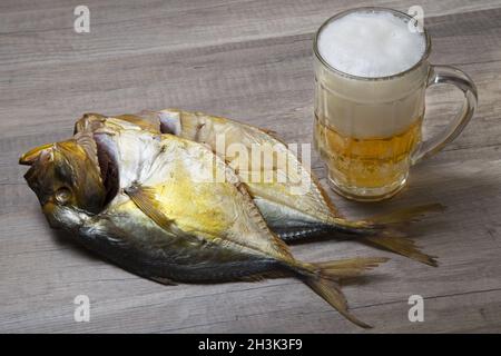 Boccale di birra e pesce essiccati su un tavolo di legno. Foto Stock