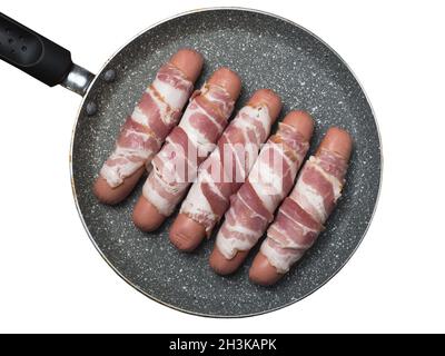 Preparazione di salsicce crude avvolte a spirale in pancetta su una padella. Vista dall'alto, su sfondo bianco Foto Stock