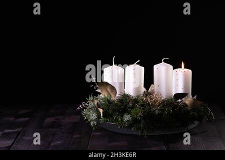 Primo Avvento - corona d'Avvento da rami di abete e sempreverdi con candele bianche che bruciano su tavola di legno scuro. Tradizione nel tempo prima di Natale. Foto Stock