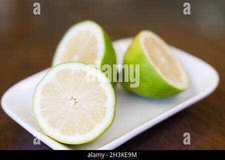 Closeup su metà di lime su piastra piccola. Fette di limone verde Foto Stock