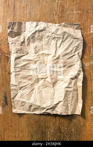 Foglio di carta vuoto stropicciato su un tavolo di legno Foto Stock