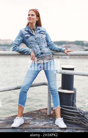 Felice giovane rossa caucasica donna guardando in su sul lungofiume Foto Stock