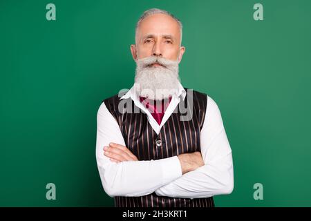 Foto di bel ben curato uomo vecchio barbuto incrociate braccia indossare vestito a righe su sfondo verde Foto Stock
