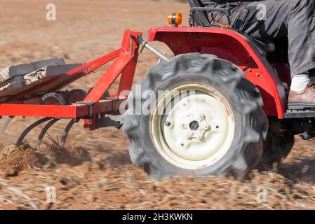 Trattore rosso con campo di aratura basso Vista ravvicinata suolo. Foto Stock