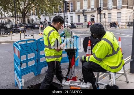 'G.Network' ingegneri che collegano cavi di rete Internet a banda larga in fibra all'interno di un 'nodo' box, nella zona Fitzrovia di Londra, Inghilterra, Regno Unito Foto Stock