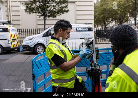 'G.Network' ingegneri che collegano cavi di rete Internet a banda larga in fibra all'interno di un 'nodo' box, nella zona Fitzrovia di Londra, Inghilterra, Regno Unito Foto Stock