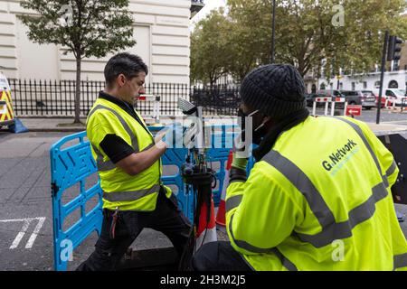 'G.Network' ingegneri che collegano cavi di rete Internet a banda larga in fibra all'interno di un 'nodo' box, nella zona Fitzrovia di Londra, Inghilterra, Regno Unito Foto Stock