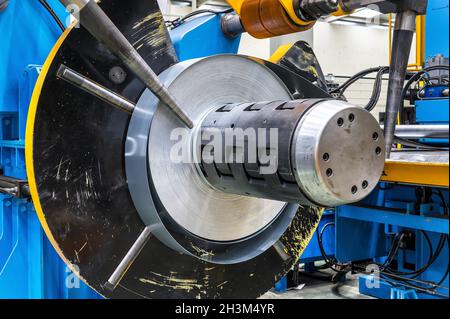 Bobine di lamiera industriale collegate alla macchina per la formatura di profili di lamiera. Foto Stock