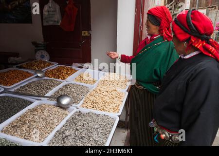 Due donne tibetane / etniche del Tibet, residenti o locali alle mura antica città cinese (antica città fortificata) di Songpan, shopping in un negozio di cibo intero che vende semi e noci, nel nord Sichuan, Cina (125) Foto Stock