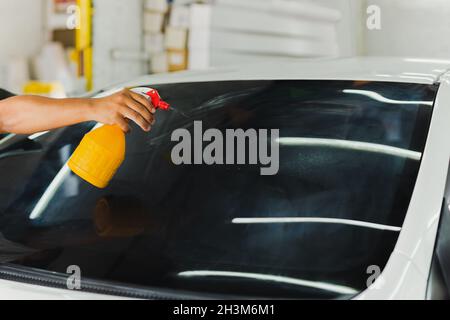Specialista dell'auto spruzzare acqua nel finestrino colorato dell'auto in officina. Foto Stock