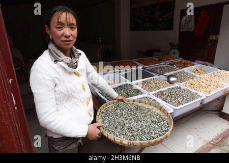 Donna tibetana / donne etniche del Tibet, residente o locale alla città cinese murata antica (antica città murata) di Songpan nel nord Sichuan, Cina. Sta vendendo semi di semi / girasole al suo negozio di tipo di cibo intero nella città. (125) Foto Stock