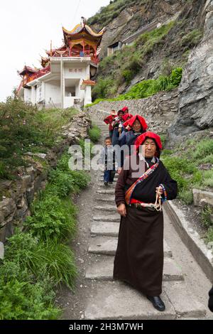 Un gruppo di adoratori buddisti cammina un sentiero / percorso da un piccolo tempio sopra la città; donne tibetane / donne etniche del Tibet, residenti o locali alla città cinese murata (antica città murata) di Songpan nel nord di Sichuan, Cina. Nel buddismo una donna può essere una suora. (125) Foto Stock