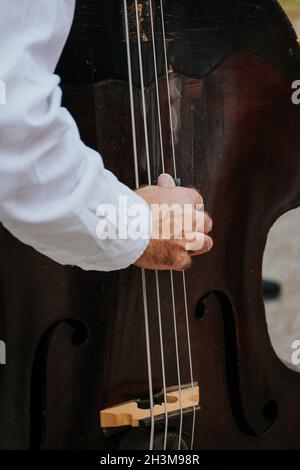 Colpo verticale di un uomo che suona un violoncello marrone scuro Foto Stock