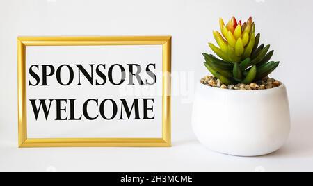 BENVENUTO LE parole DELLO SPONSOR scritte su una cornice fotografica dorata, accanto a un cactus su sfondo bianco Foto Stock