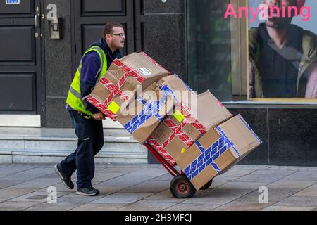 Il conducente consegna pacchi per il negozio Office City Center, catena di scarpe on-trend che vende calzature con marchio proprio e di marca, i grandi magazzini di alta strada vendono scorte di vendita su camion a sacco gommato 2 per servizi pesanti. Preston, Regno Unito Foto Stock