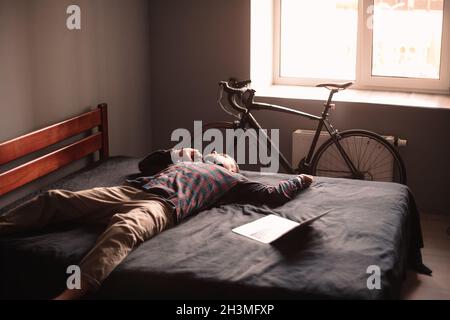 Uomo stanco che parla su smartphone sdraiato a casa Foto Stock