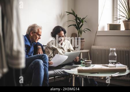 I proprietari senior di sesso maschile e femminile hanno un brainstorming sul laptop in officina Foto Stock