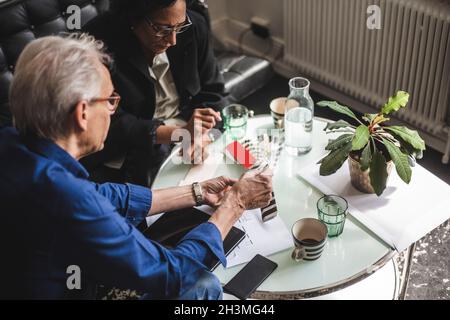 Vista ad alto angolo dei proprietari di sesso maschile e femminile che discutono al tavolo in ufficio Foto Stock