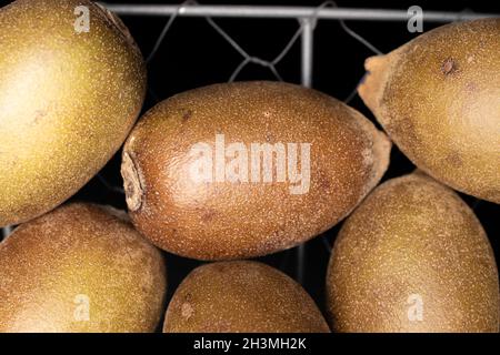 Diversi kiwi biologici succosi con un cestino, primo piano, isolato su nero. Foto Stock