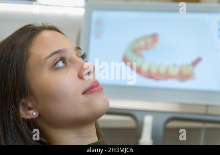 Grande concetto di procedura dentale, giovane donna bionda brasiliana nella sedia dentale che soffre procedura dentale dal dentista come uso di monito di visualizzazione Foto Stock