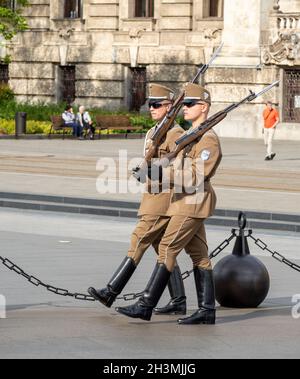 Due soldati Marchig: Due soldati, in servizio di guardia del Parlamento ungherese, marciano all'unisono con le loro armi intorno a Kossuth Lajos Ter. Foto Stock